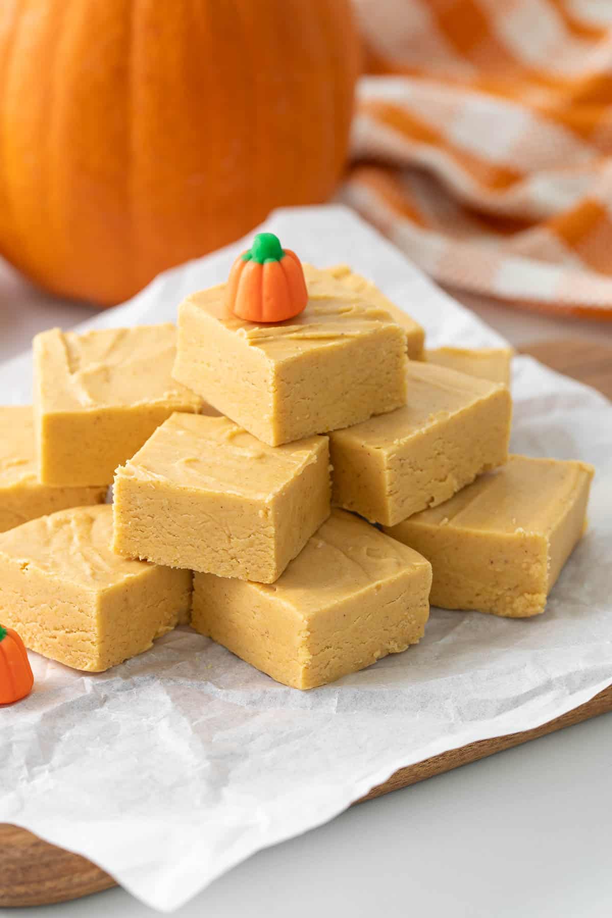 Angled view of pumpkin fudge squares topped with a small candy pumpkin.