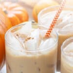 Front view of a pumpkin spice white Russian with an orange and white paper straw. Overlay text is at the top of the image.