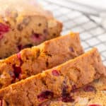 Front close up view of a partially sliced loaf of cranberry apple bread. Overlay text is at the top of the image.