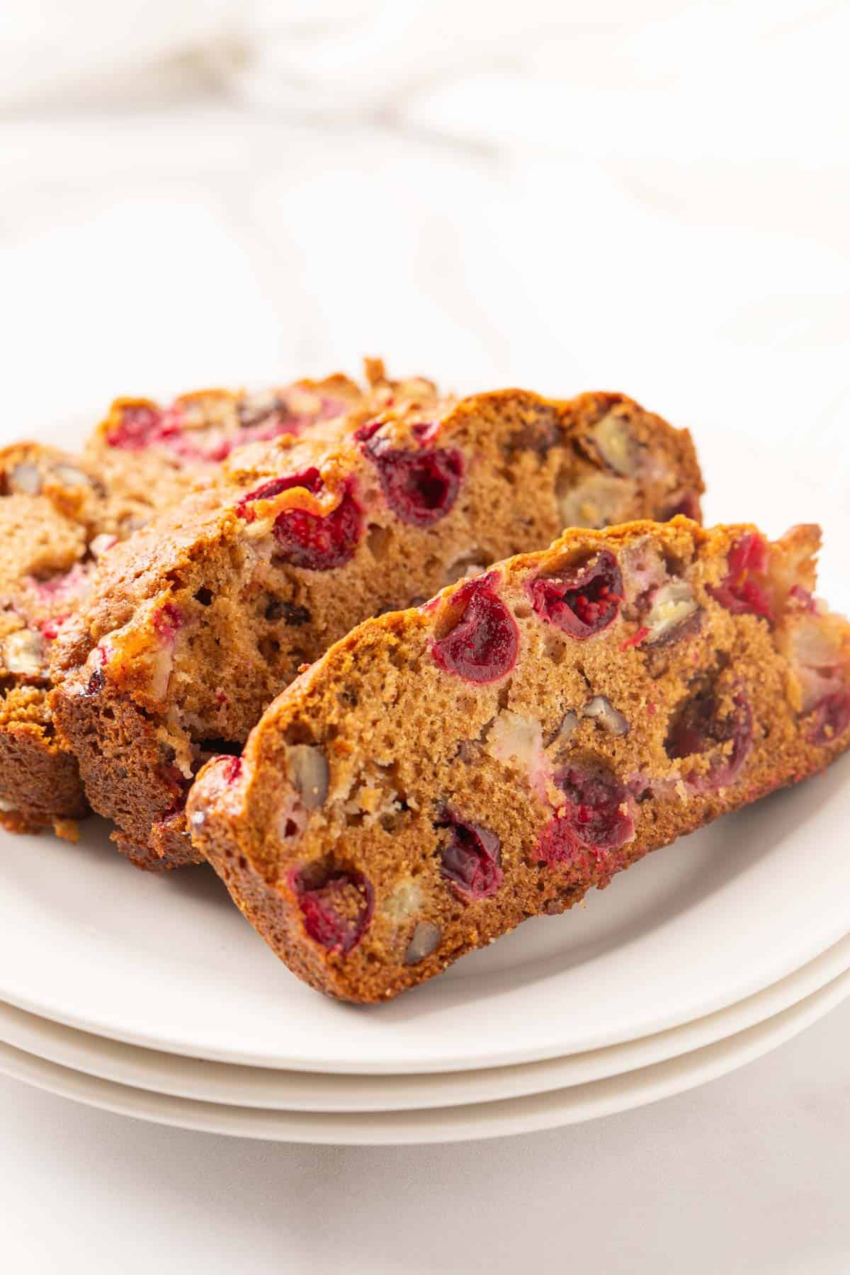 Three slices of cranberry apple bread on a small white plate.