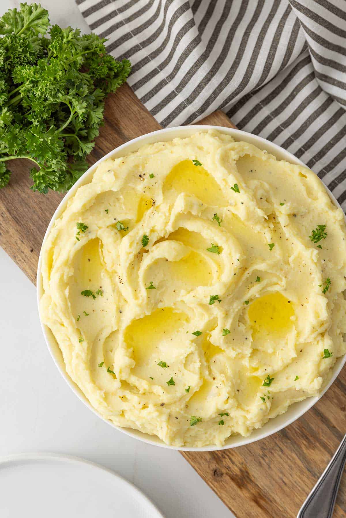 Overhead view of a bowl of cream cheese mashed potatoes sprinkled with parsley.