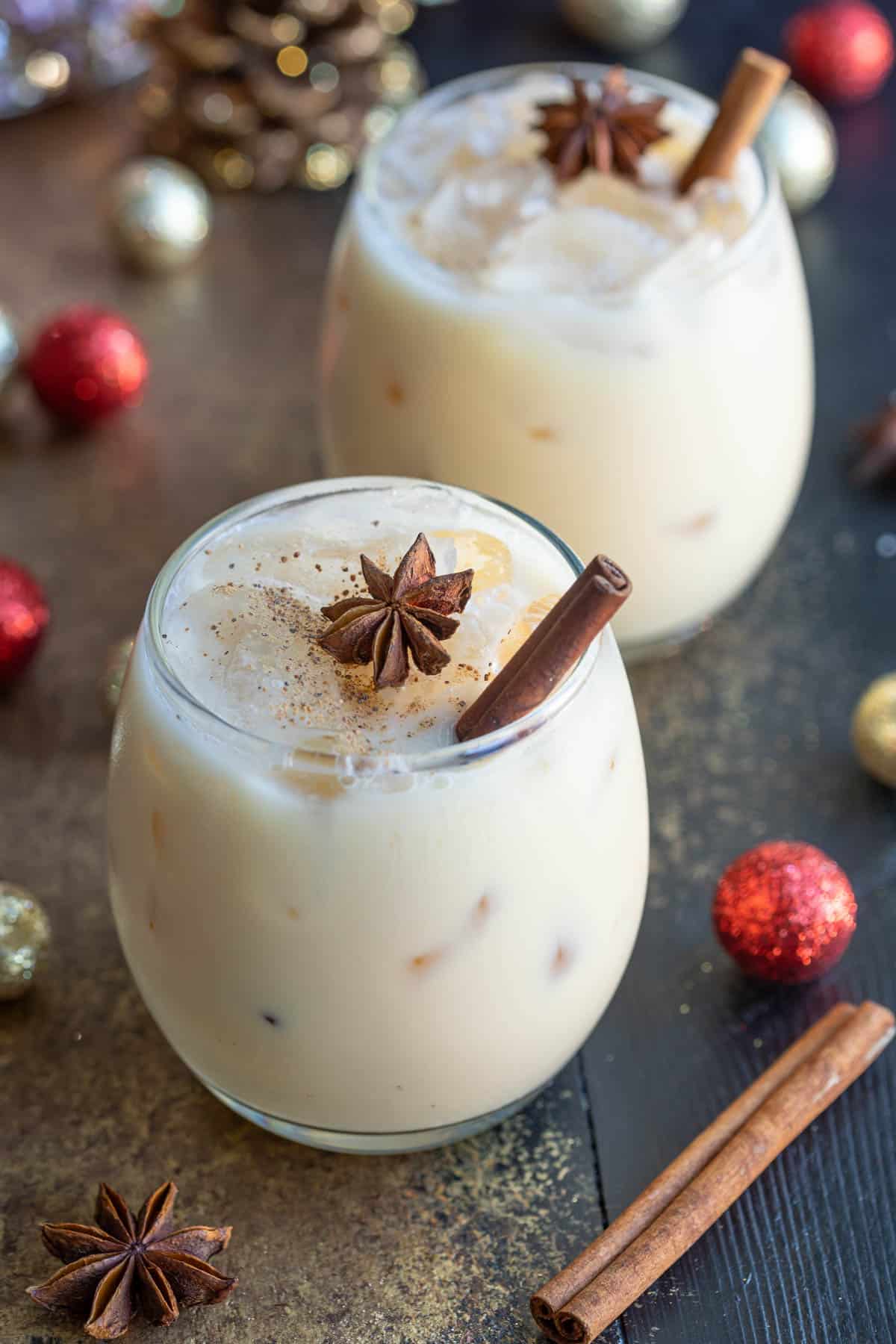 Front view of two eggnog white Russian cocktails garnished with nutmeg, star anise, and a cinnamon stick.
