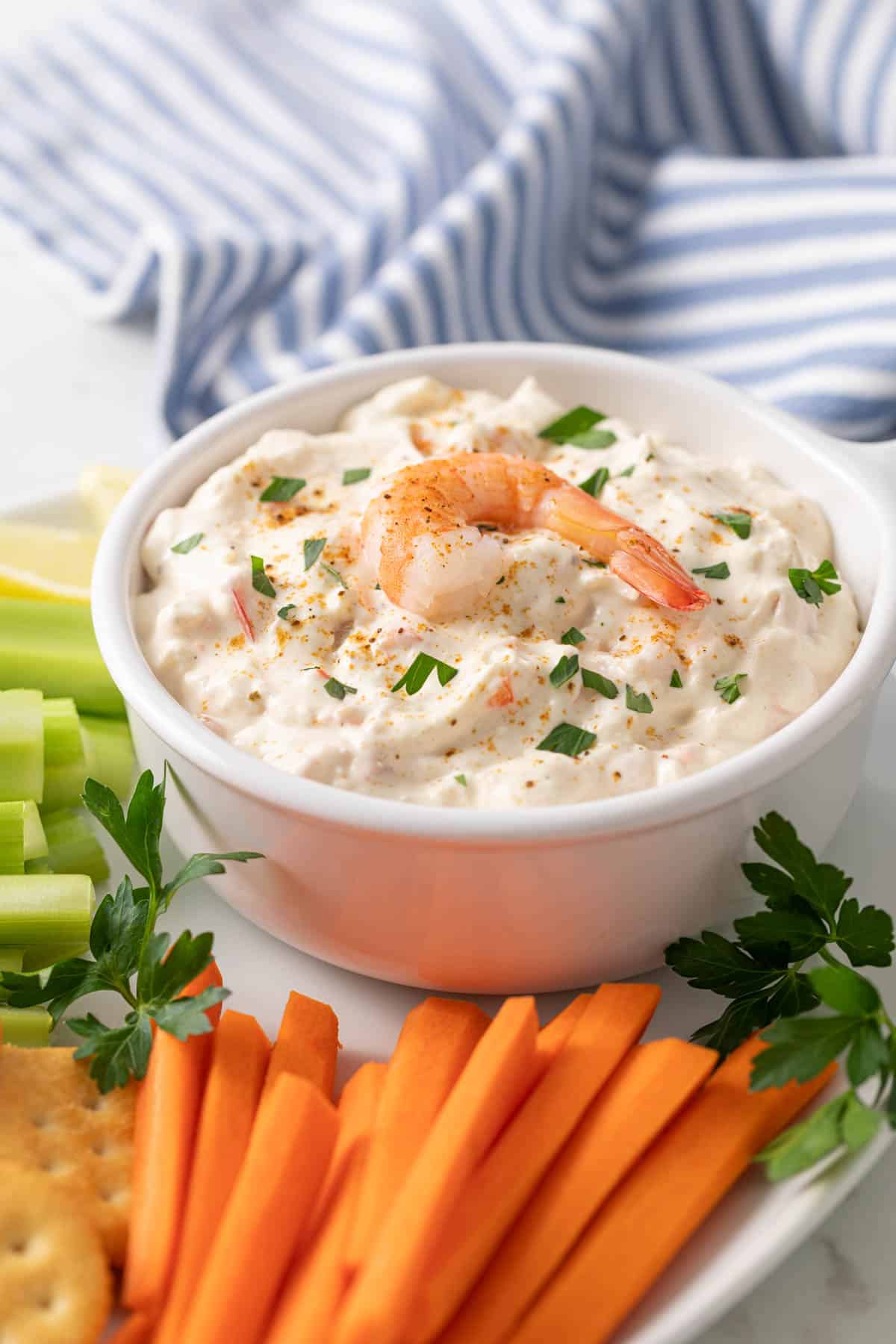Front angled view of a bowl of shrimp dip on a platter.