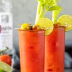 Front view of two bloody mary cocktails with garnishes.