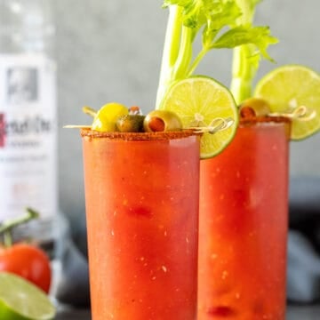 Front view of two bloody mary cocktails with garnishes.