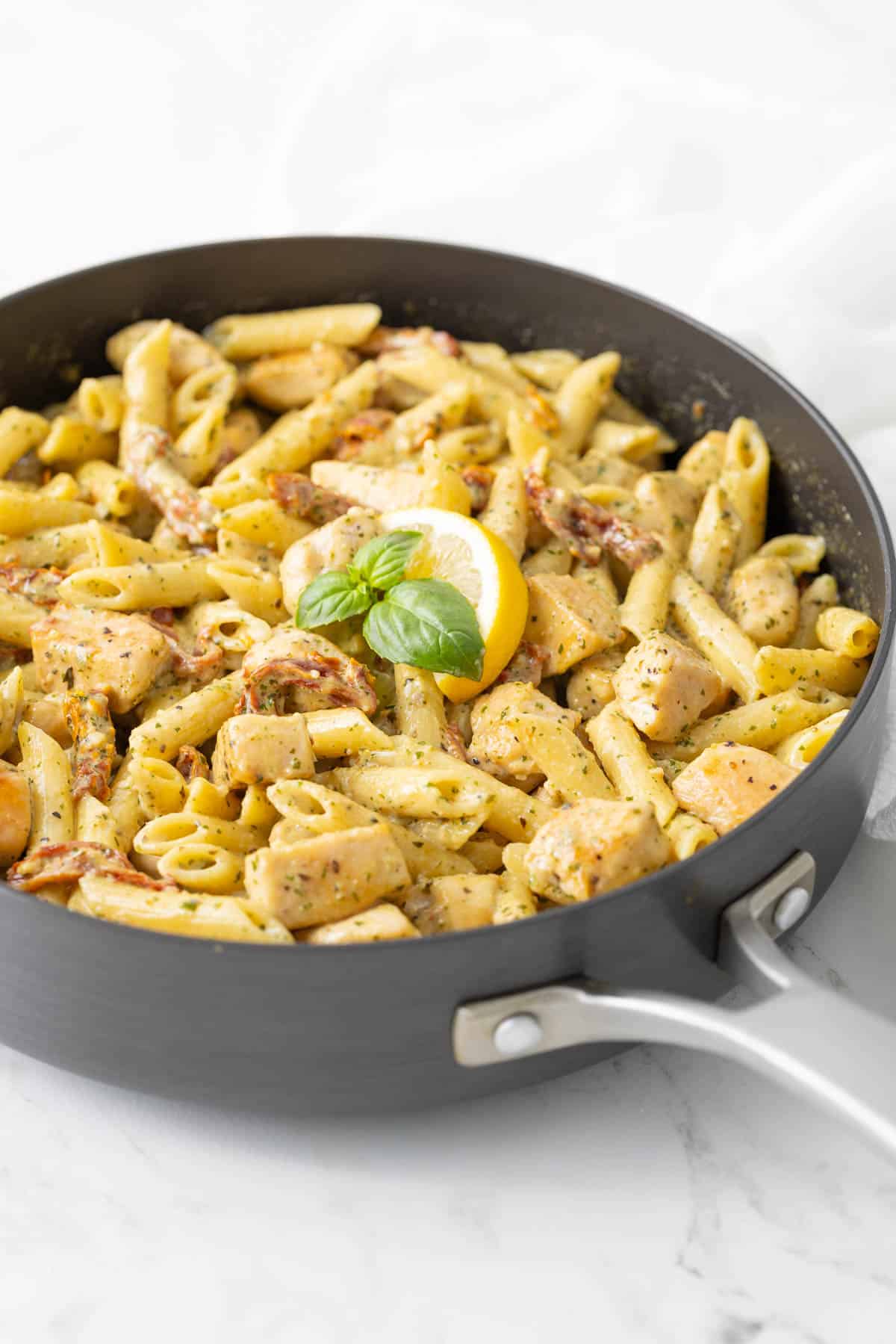 Creamy chicken and pesto pasta in a skillet.