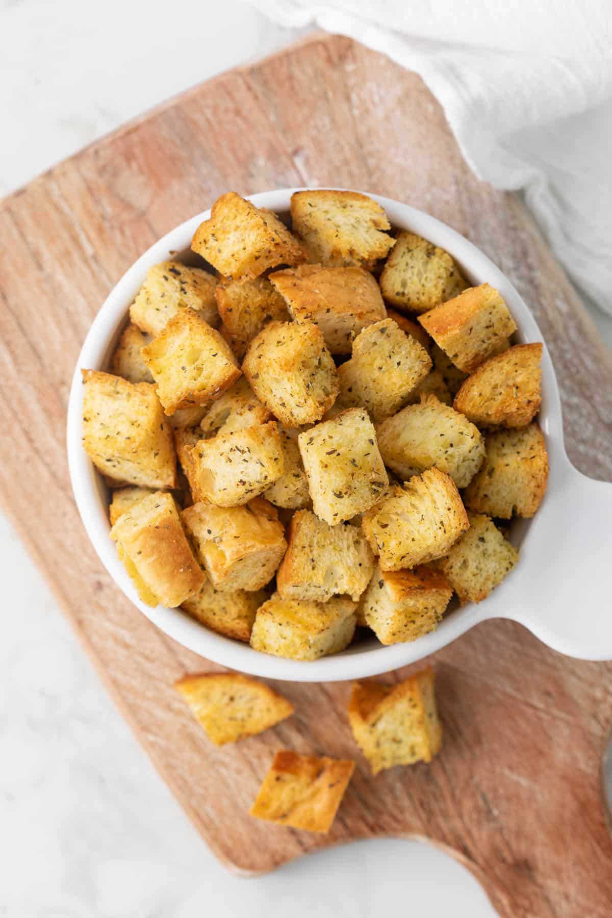 Overhead view of homemade croutons in a white bowl.