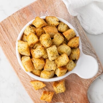 Overhead view of homemade croutons in a white bowl.