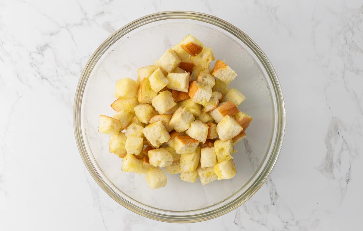 A bowl of French bread cubes that have been tossed with olive oil.