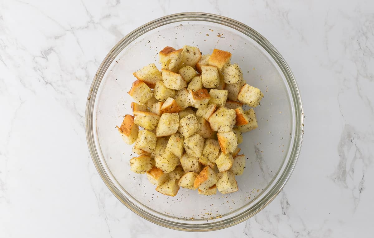 A bowl of French bread cubes tossed with olive oil, Italian seasoning, salt, pepper, and garlic powder.