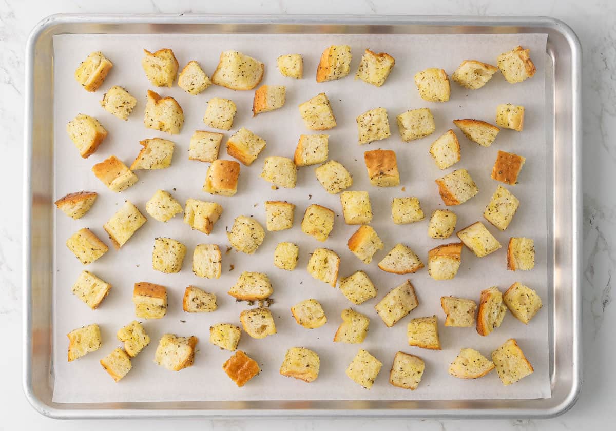 Croutons on a baking sheet lined with parchment paper before baking.
