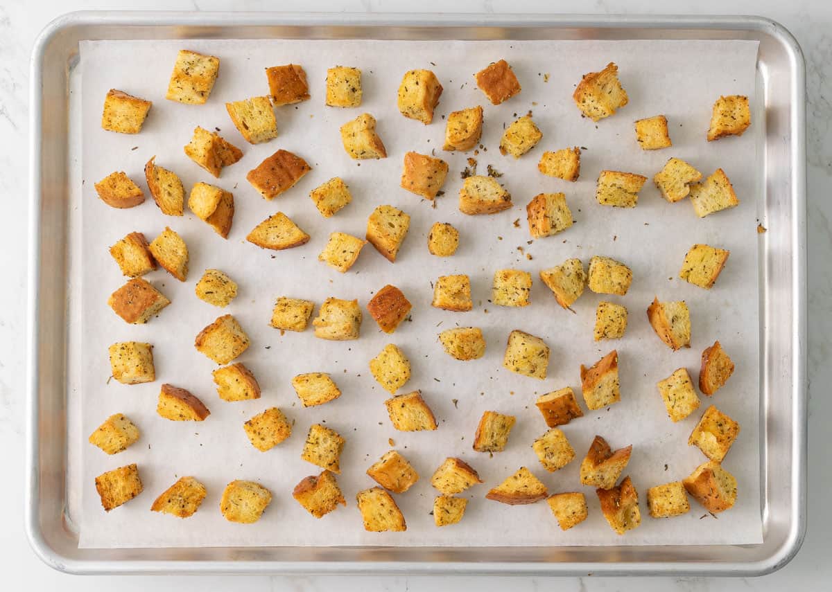 Croutons on a baking sheet lined with parchment paper after baking.