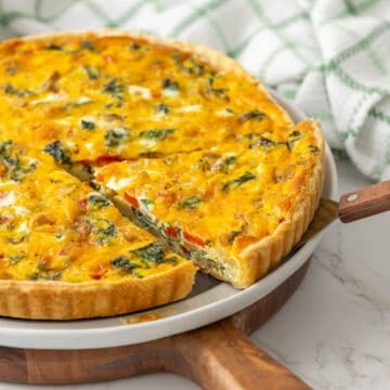 A slice of kale quiche is being removed with a spatula.