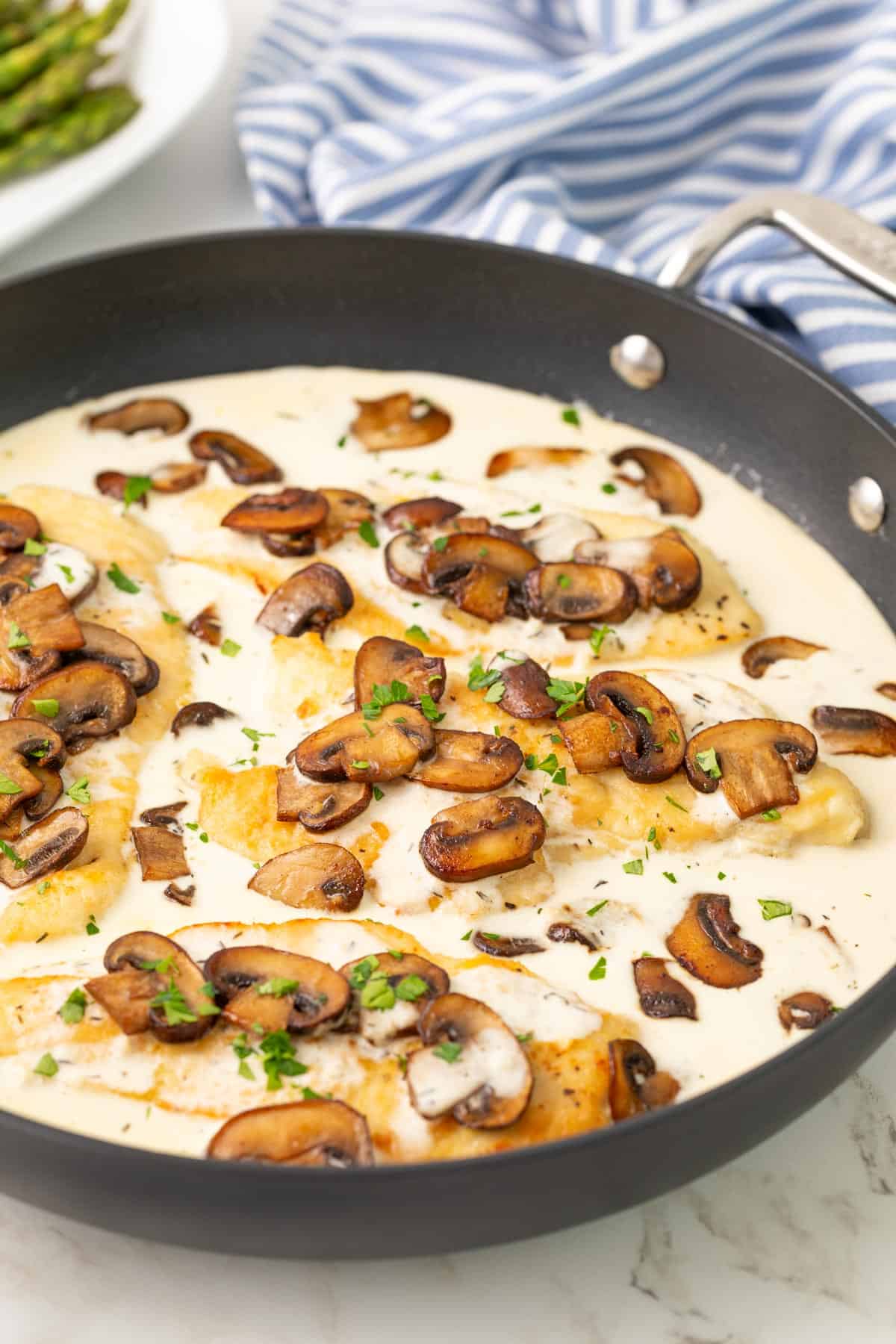 Chicken breasts in a skillet with creamy mushroom sauce.