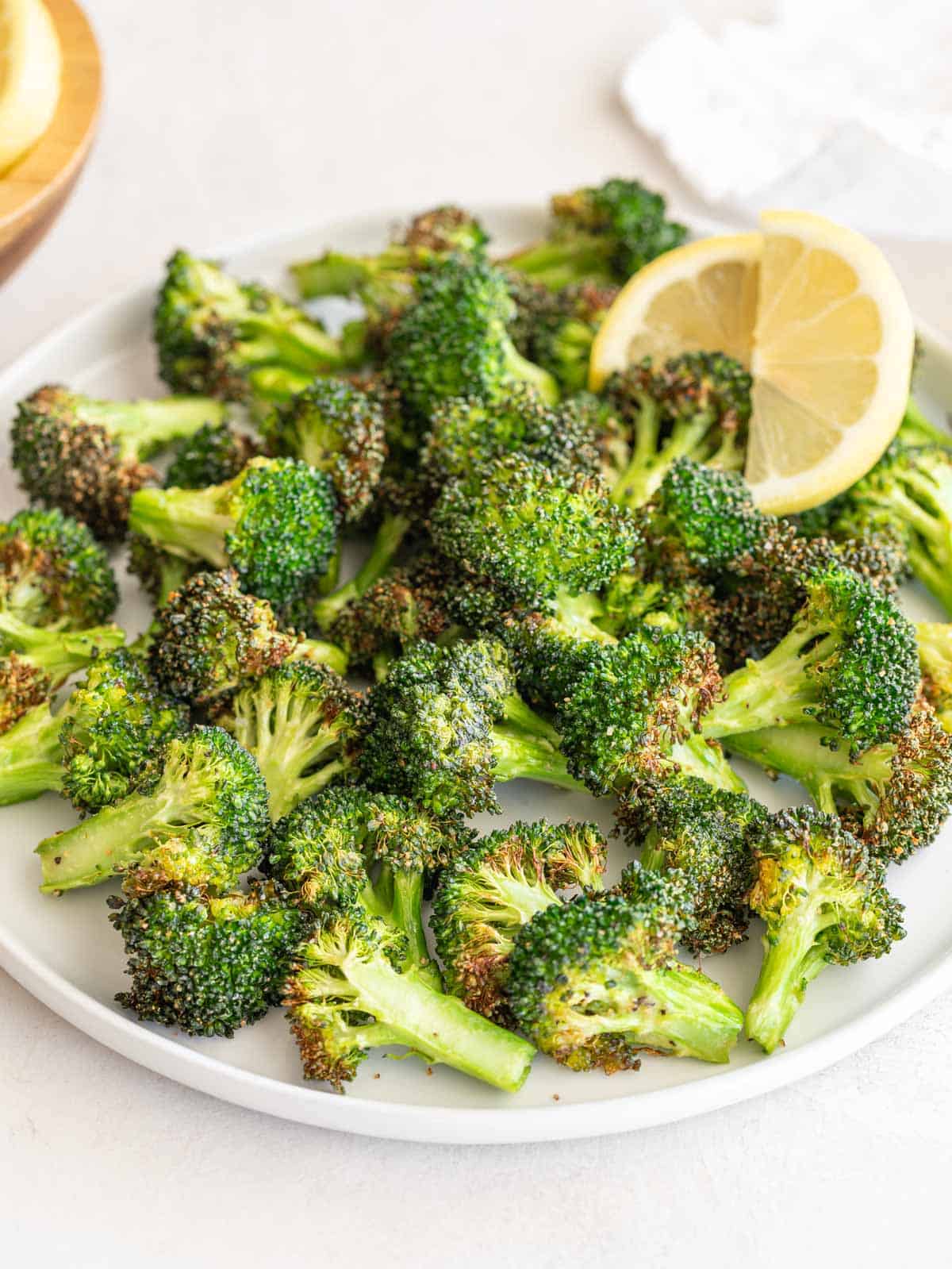 Front close up view of a plate of broccoli that has been cooked in an air fryer.