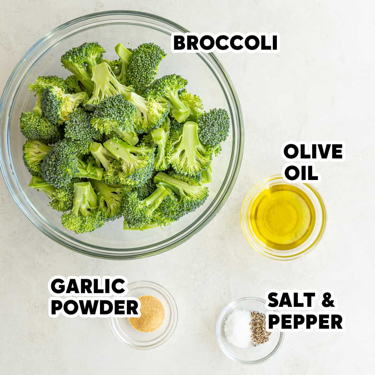 A bowl of broccoli florets, olive oil, garlic powder, salt, and pepper with overlay text.