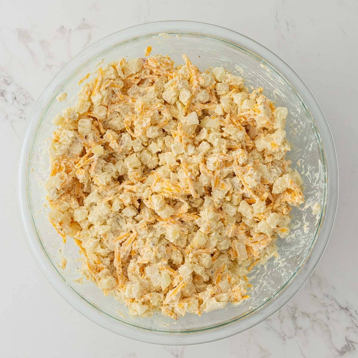 Cheesy potato mixture in a mixing bowl before going into a crock pot.