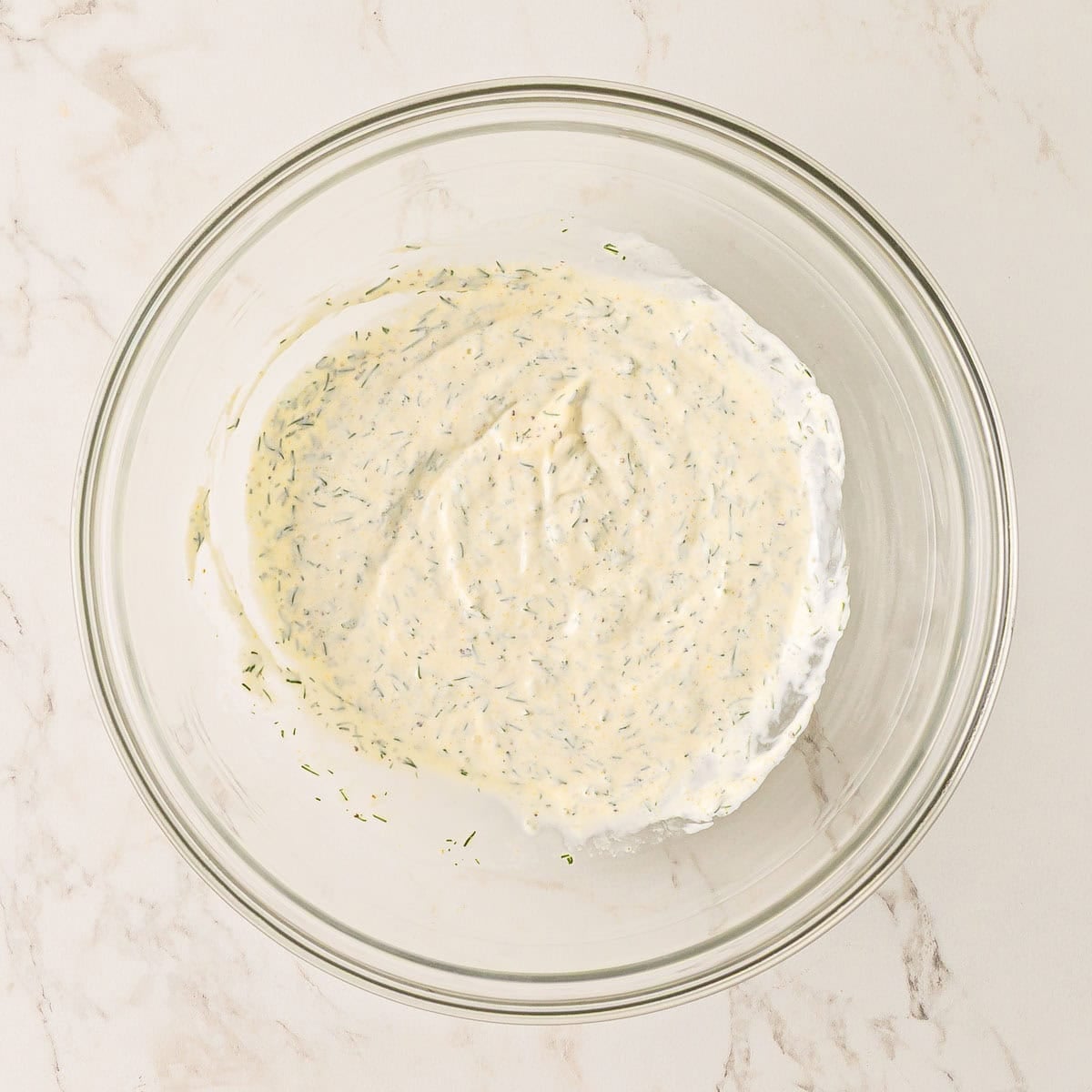 Mayonnaise, sour cream, lemon juice, garlic powder, dill, salt, and pepper combined in a medium bowl.