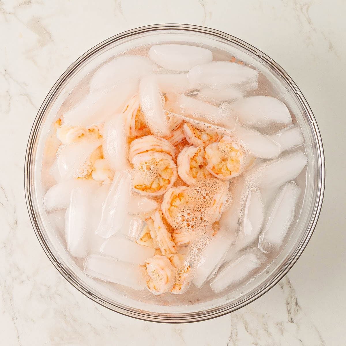 Cooked shrimp in a bowl of ice water.
