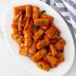 Overhead view of air fryer carrots on an oval white plate.