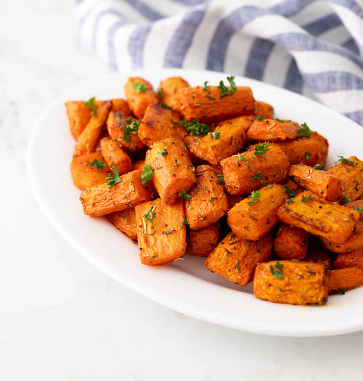 Front angled view of air fried carrots on an oval white plate.