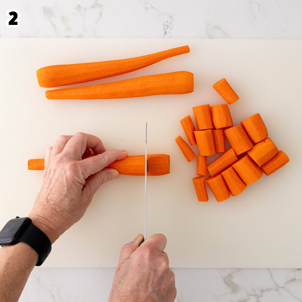 A peeled carrot is being cut lengthwise into 1-inch pieces.