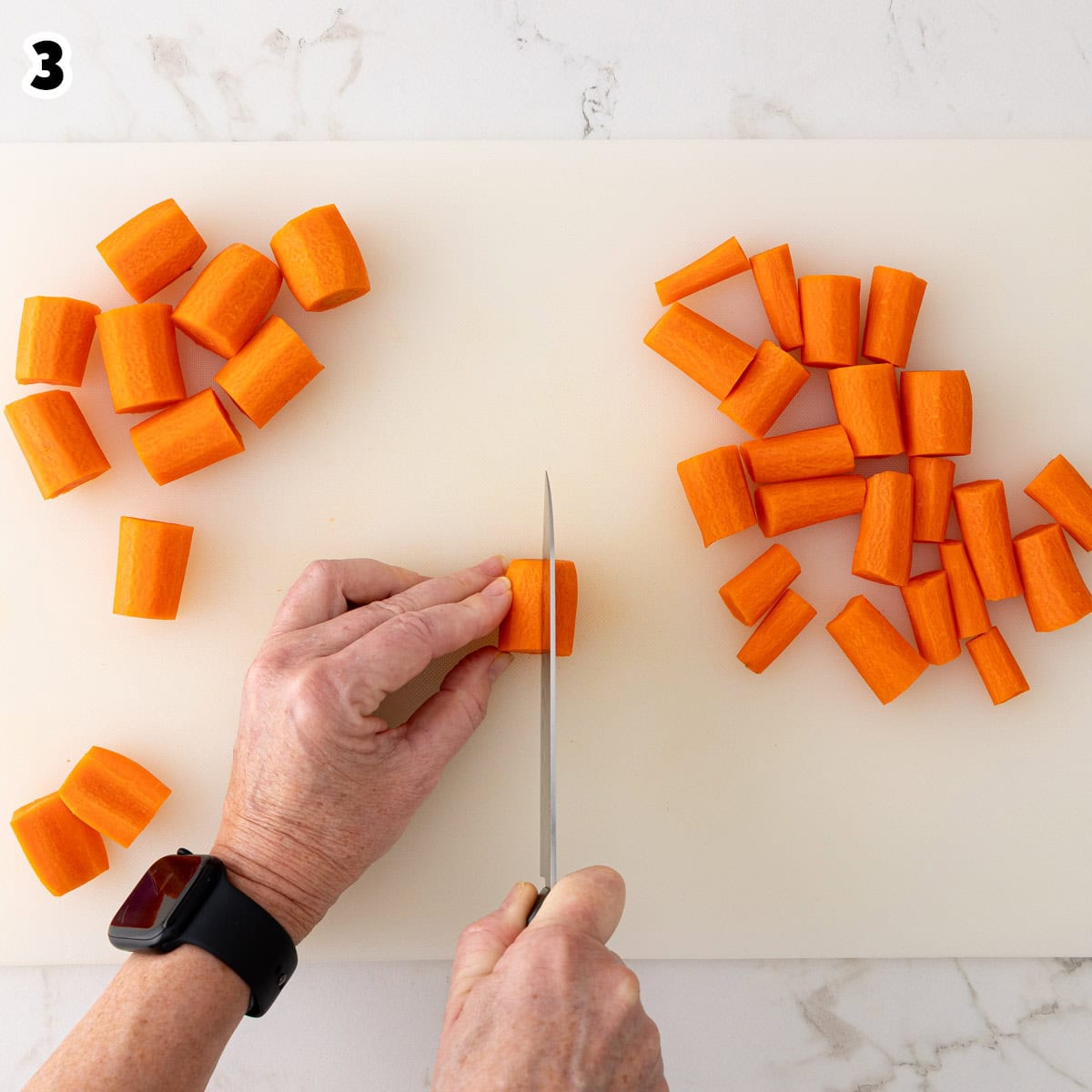 A 1-inch peeled carrot piece is being cut crosswise.