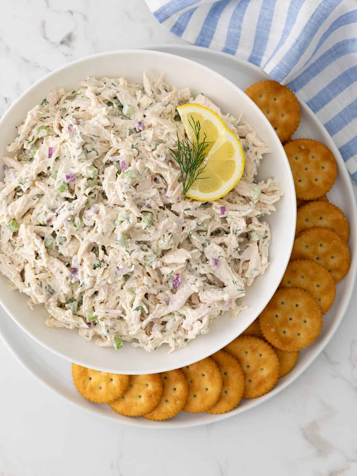 Overhead view of a bowl of classic chicken salad on a plate with crackers.