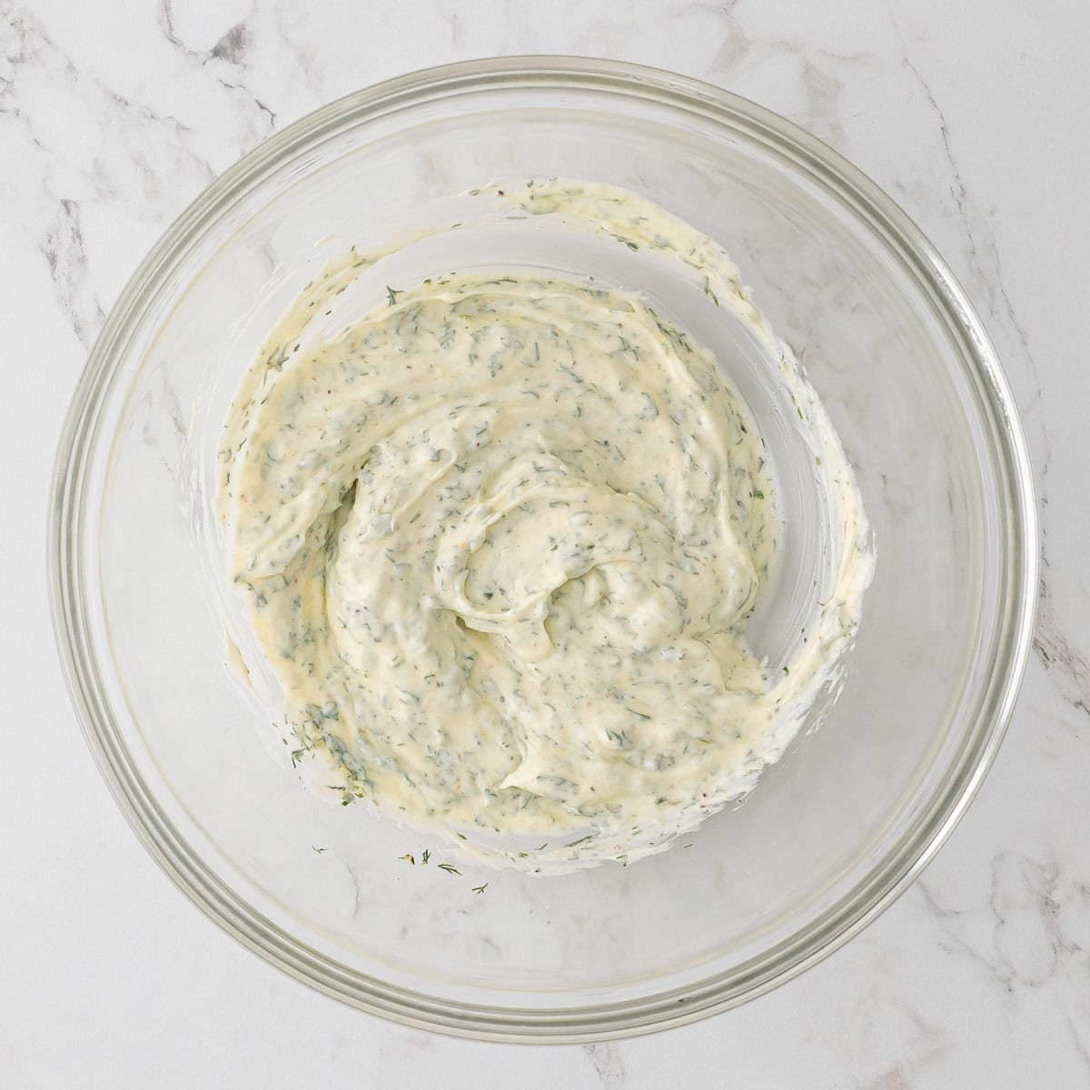 Dressing ingredients for chicken salad are combined in a glass bowl.