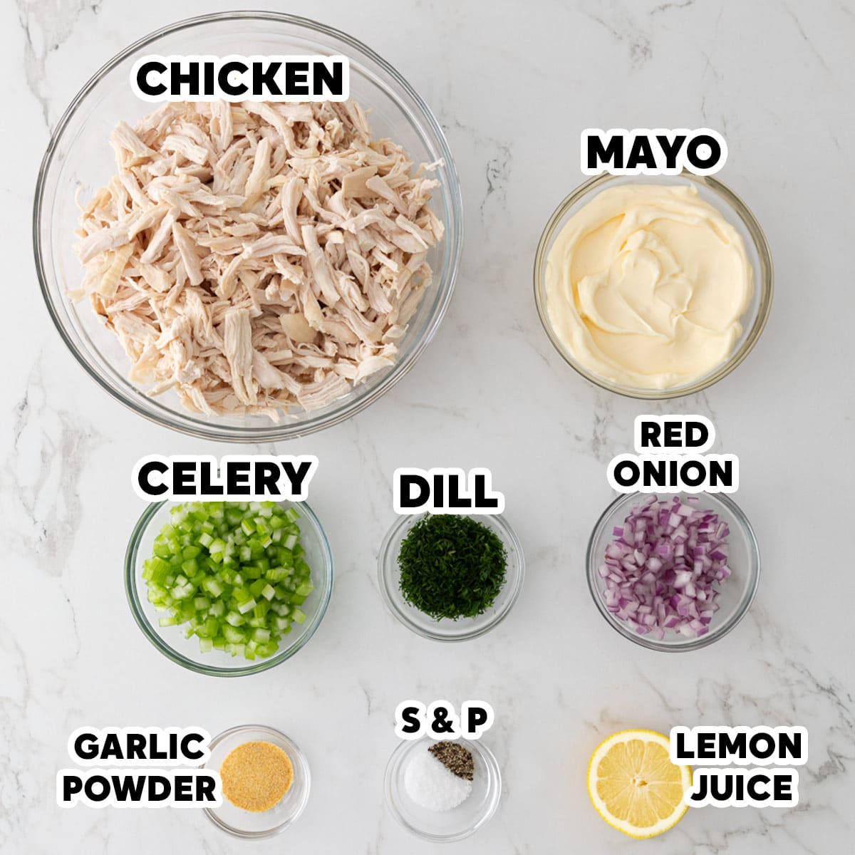 Overhead view of ingredients for making chicken salad with overlay text labeling each ingredient.